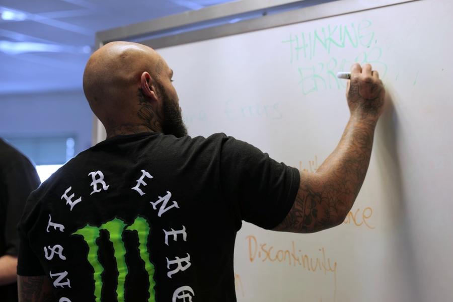 View from behind a man writing on a whiteboard. 