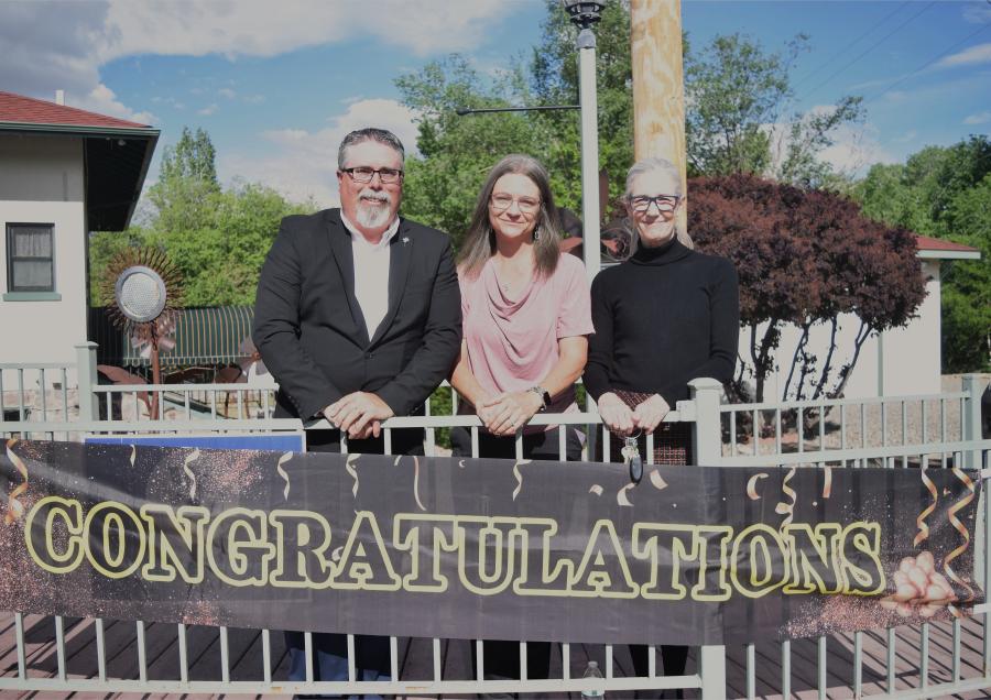 MCDHS leadership team posing in front of a "Congratulations" sign outside.