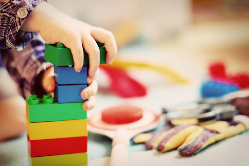 A child's hands playing with colorful lego style blocks.